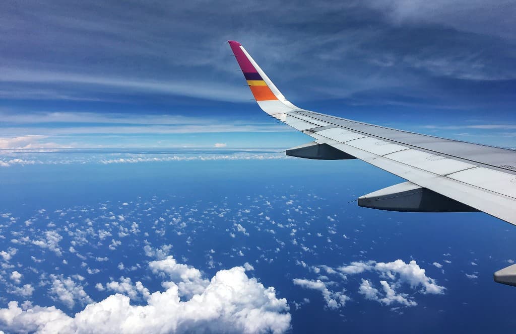 Vue depuis un hublot d’avion, au-dessus des nuages